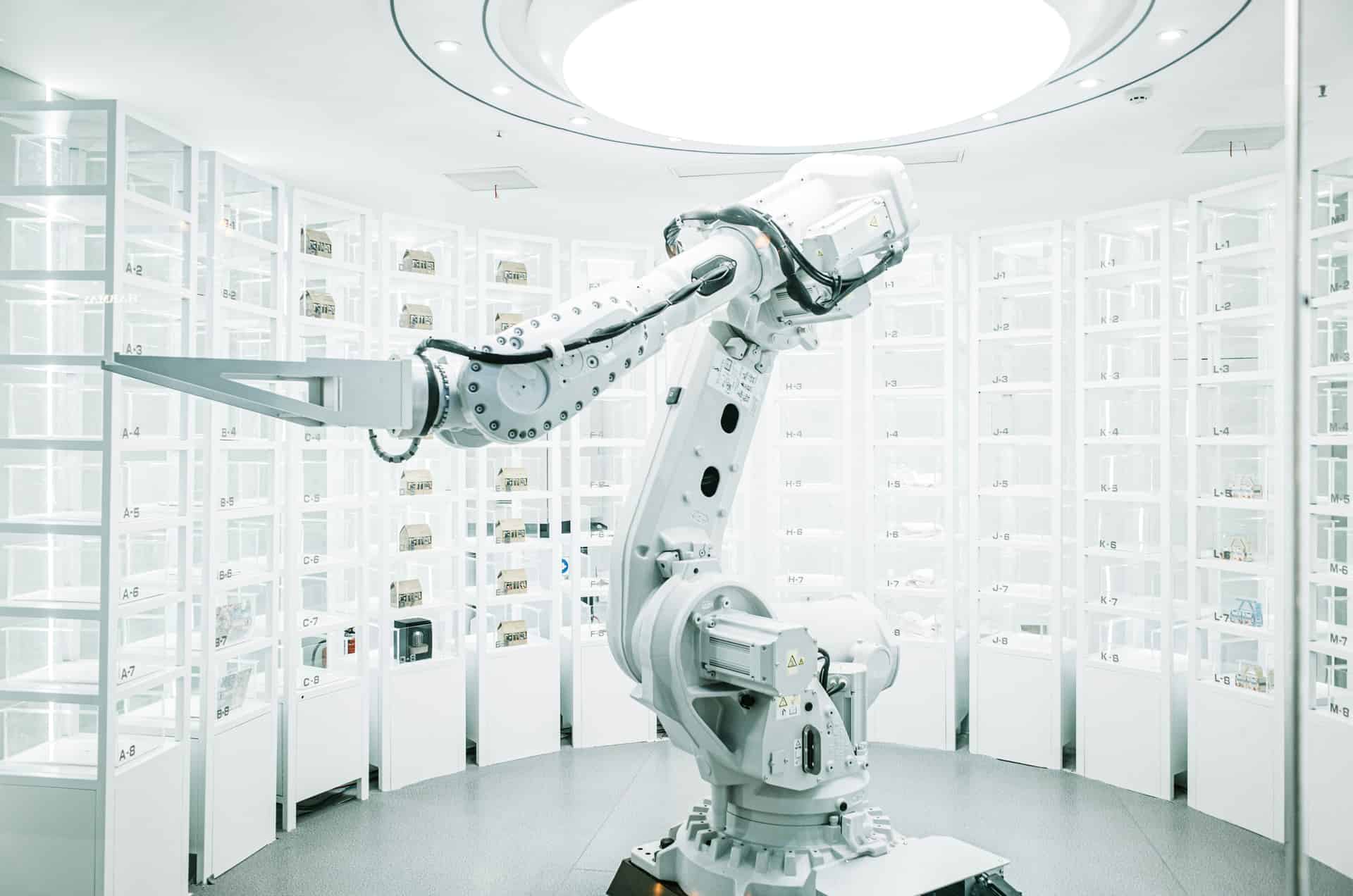 White robotic arm retrieving parts in an automated storage system